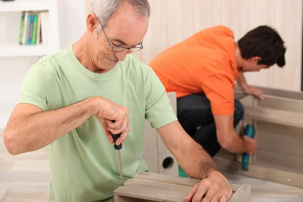Father and son putting together flatpack furniture — Stock Photo, Image