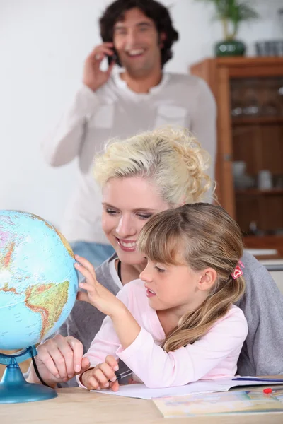 Donna aiutando sua figlia a completare i suoi compiti di geografia — Foto Stock