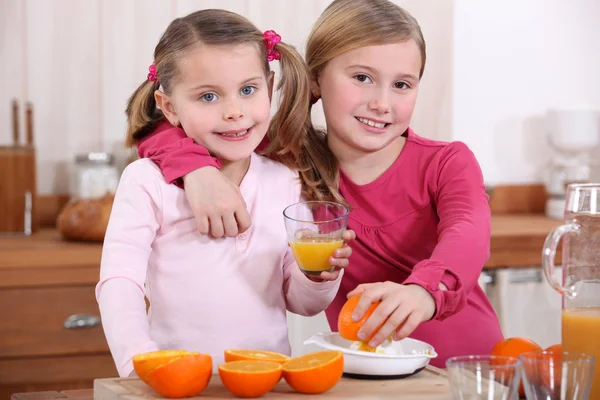 Two little girls drinking orange juice — Stock Photo, Image