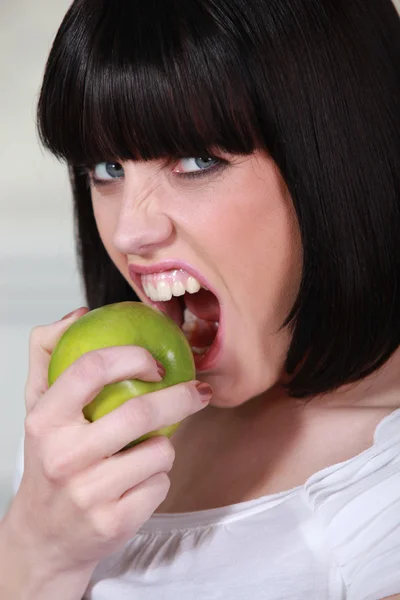 Atractiva mujer mordiendo una manzana verde crujiente —  Fotos de Stock
