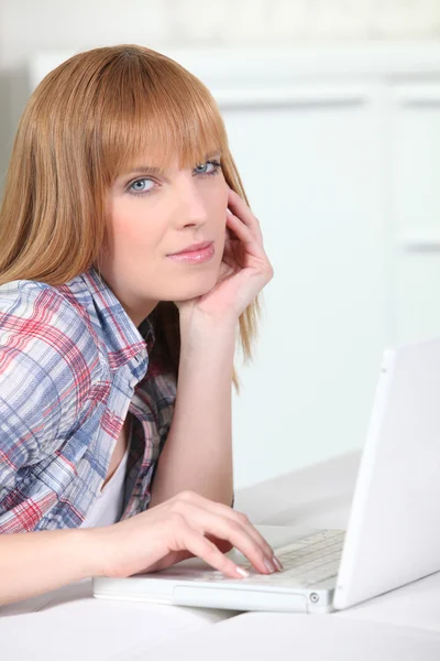 Kausale rothaarige Frau benutzt weißen Laptop — Stockfoto