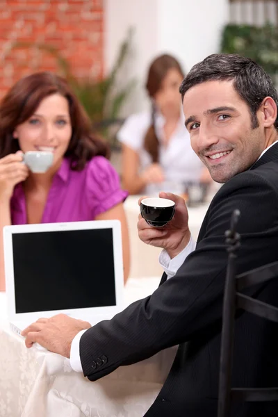 Couple drinking expresso in a cafe with a laptop screen left blank for your — Stock Photo, Image