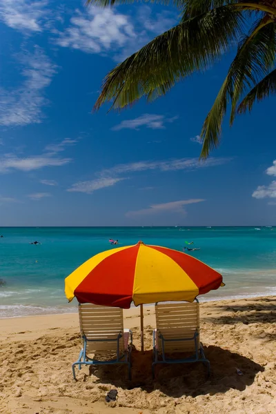 Solstolar och ett parasoll på en strand — Stockfoto