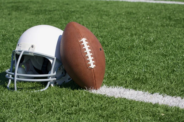 Американский профессиональный футбол и шлем на поле — стоковое фото