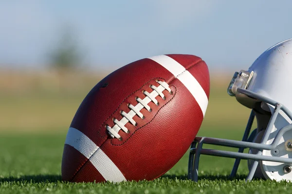 Футбол и шлем на поле — стоковое фото