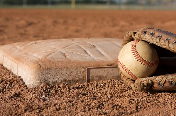 Beisebol e luva perto de uma base — Fotografia de Stock
