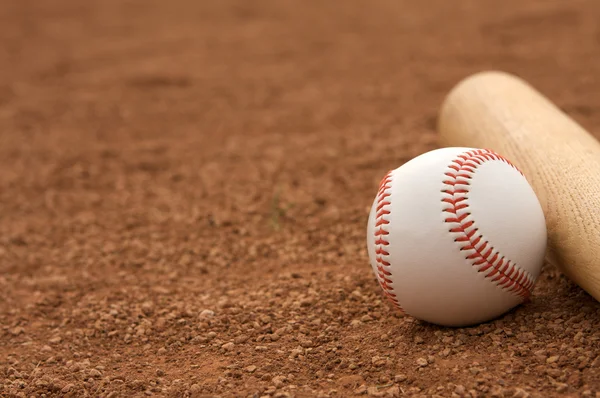 Béisbol y murciélago en la suciedad de Infield — Foto de Stock