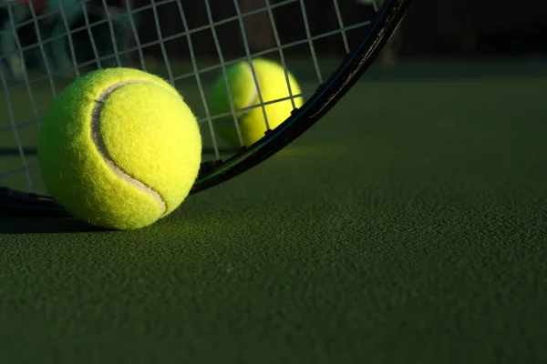Теннисные мячи и ракетка на корте — стоковое фото