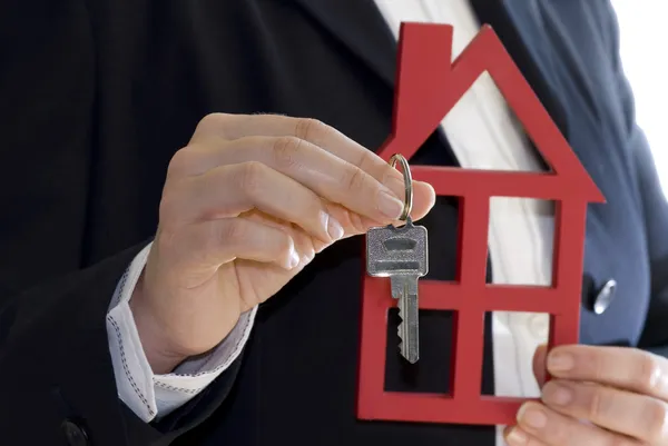 Elini tutmak bir anahtar ve bir ev Satılık — Stok fotoğraf