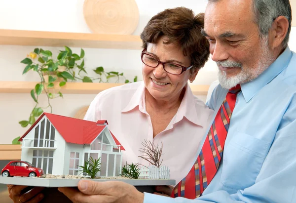 Coppia di anziani in possesso di un modello della loro casa dei sogni — Foto Stock
