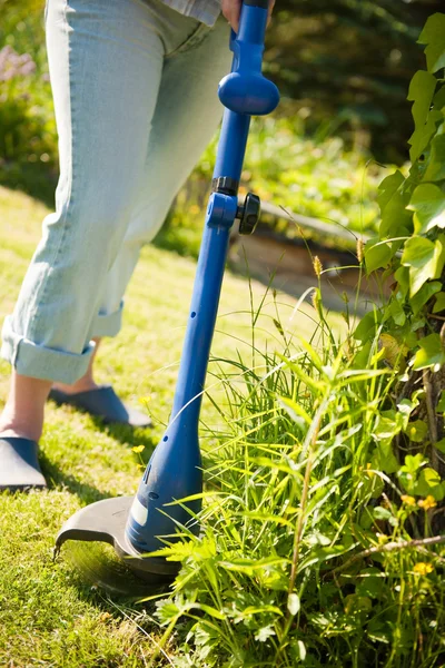 Mulher com cortador de grama na frente do quintal — Fotografia de Stock