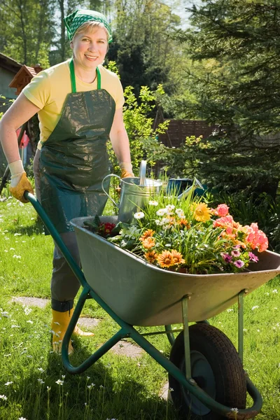 Gelukkige vrouw met bloemen in haar tuin — Stockfoto