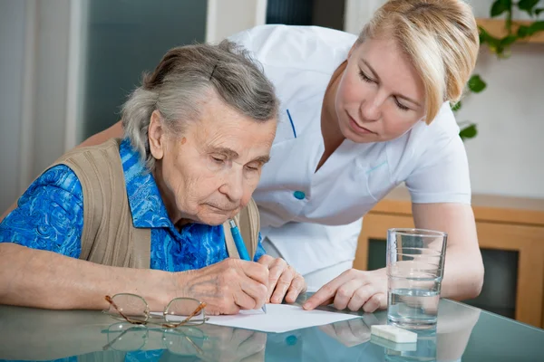 Ajudar uma mulher idosa por enfermeira em casa . — Fotografia de Stock