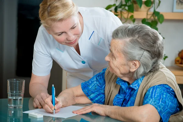 Aider une femme âgée par une infirmière à la maison . — Photo