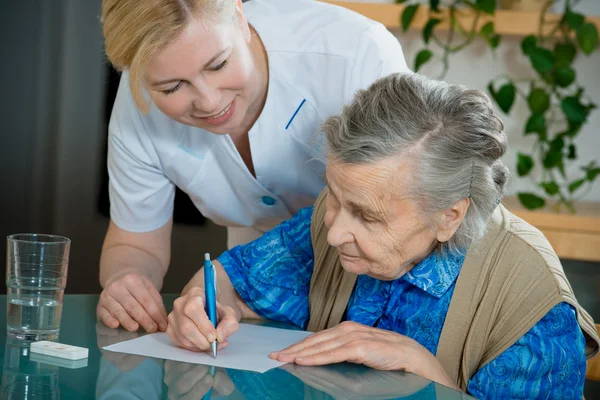 Hjälpa en äldre kvinna av sjuksköterska i hemmet. — Stockfoto