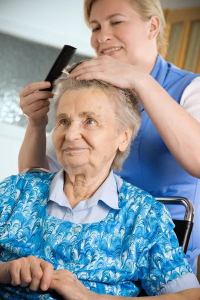 Krankenschwester kleidet die Haare einer Seniorin — Stockfoto