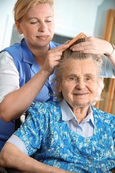 Sjuksköterska klä håret av en äldre kvinna — Stockfoto