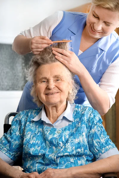 Νοσοκόμα να ντύσει τα μαλλιά μιας ανώτερος γυναίκας — Φωτογραφία Αρχείου