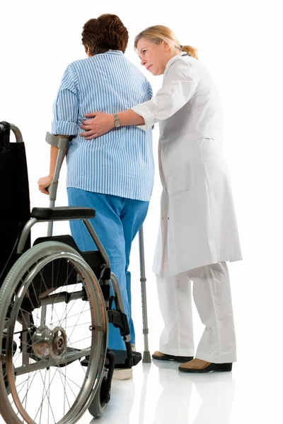 Infirmière aide une femme âgée sur des béquilles — Photo