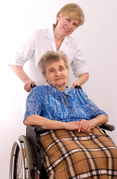 Enfermera joven animando a una mujer mayor en silla de ruedas — Foto de Stock