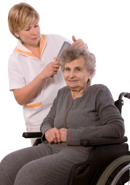 Медсестра одевает волосы пожилой женщины — стоковое фото