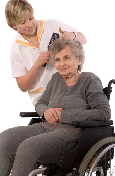 Verpleegkundige omhoog het kleden van de haren van een senior vrouw — Stockfoto