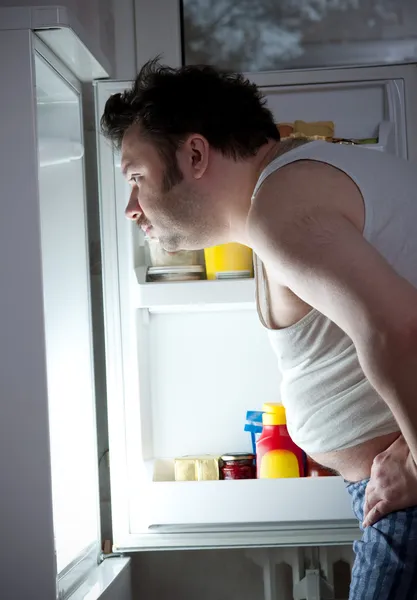Товстий чоловік отримує пиво з холодильника — стокове фото