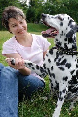 Woman playing with the dog in park clipart