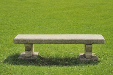 Stone bench on green field clipart