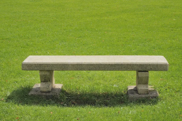 Kamienną ławeczkę na zielone pole — Zdjęcie stockowe