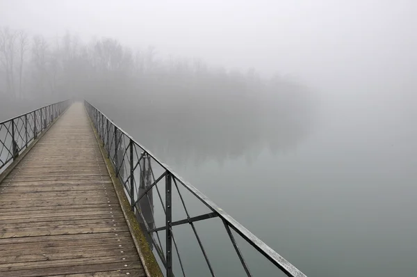 stock image Pedestiran bridge in fog, adda river