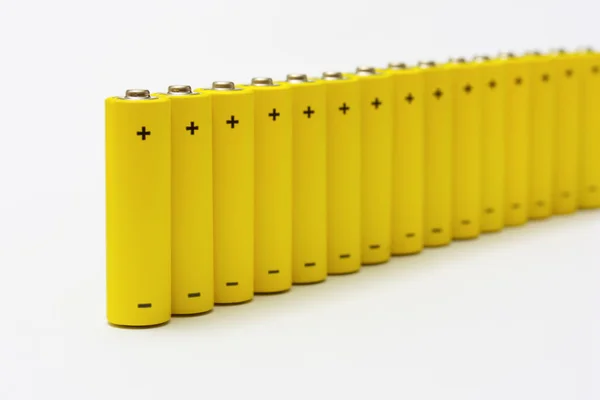 Ряд желтых анонимных щелочных батарей — стоковое фото