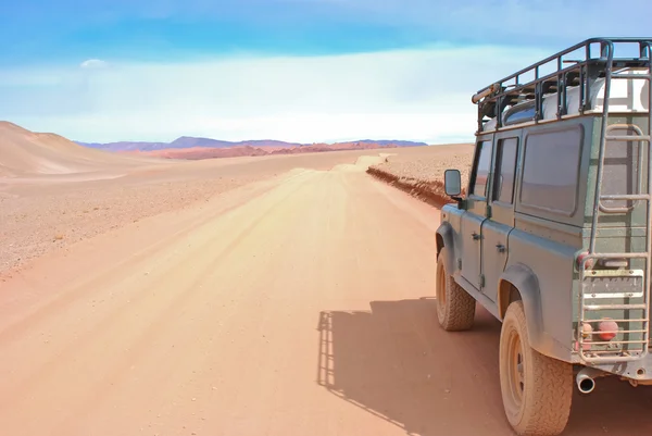 Czerwony droga pustyni i land rover — Zdjęcie stockowe