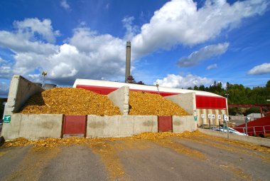 Bio power plant with storage of wooden fuel against blue sky clipart