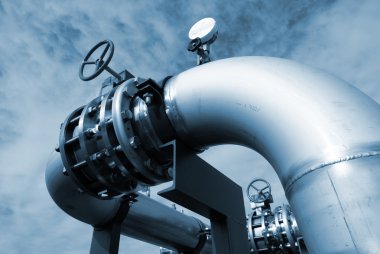 Industrial pipelinesand valve on pipe-bridge against blue sky clipart