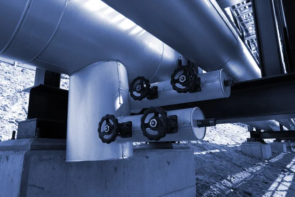 Industrial pipelines and valve on pipe-bridge against blue sky — Stock Photo, Image