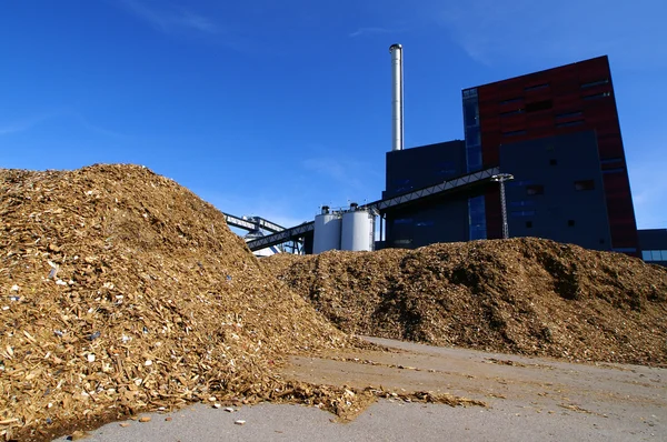 Bioelektrárna se skladováním dřevěného paliva proti modré obloze — Stock fotografie