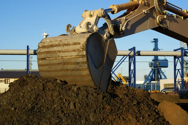 Excavadora hidráulica en el trabajo. Cubo de pala contra el cielo azul —  Fotos de Stock