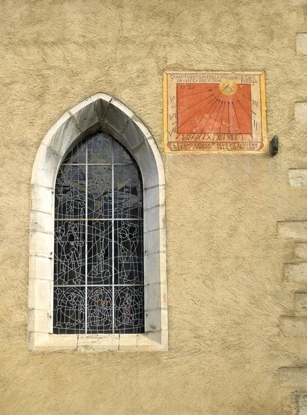 Anciant church window with sun dial on a stone wall — Stock Photo, Image