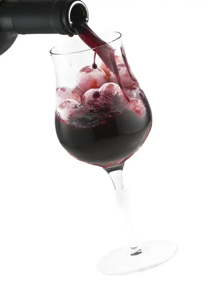 Red wine pouring down in a glass with grapes — Stock Photo, Image