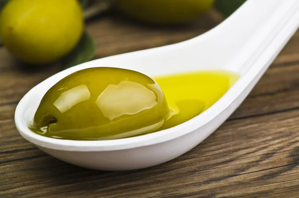 Zelené olivy a olej na lžíci — Stock fotografie