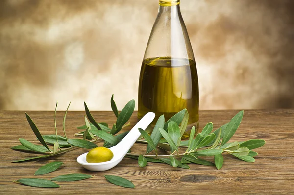 Zelené olivy naložené ve lžíci drobet láhev a list — Stock fotografie