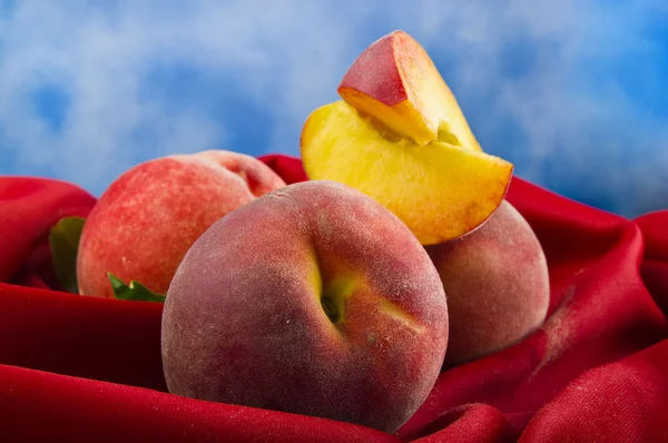 Fresh peach fruits with cut on red velvet — Stock Photo, Image