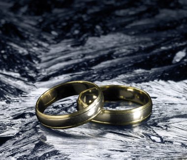 Two golden wedding rings on ice surface clipart