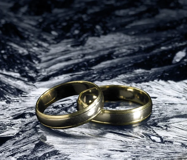 Dois anéis de casamento dourados na superfície do gelo — Fotografia de Stock