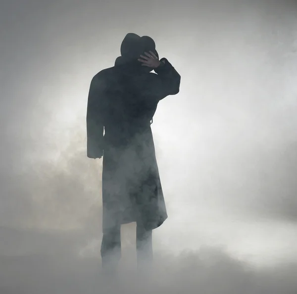 Kvinna klädd i trenchcoat och står i dimma — Stockfoto