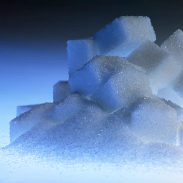 Montón de azúcar en terrón iluminado azul — Foto de Stock