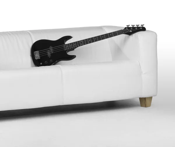 Guitare basse noire sur canapé blanc — Photo