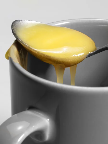 Cup and honey spoon — Stock Photo, Image
