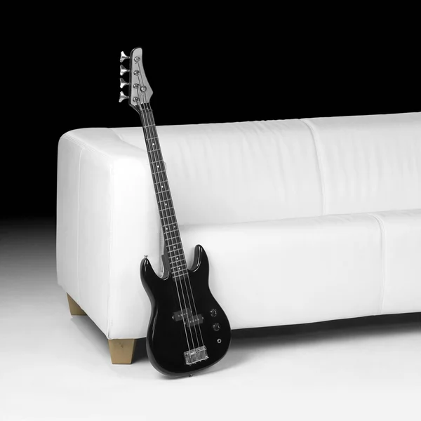 Schwarze Bassgitarre und weißes Sofa — Stockfoto
